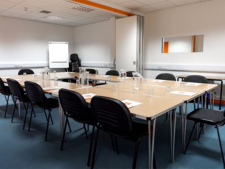 Meeting Room 2 with a large table surrounded by twelve chairs and a flipchart in the corner.